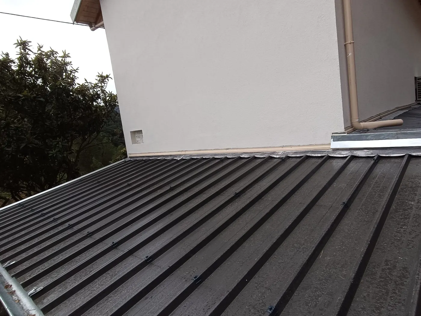 Toiture en bac acier avec solin contre une façade